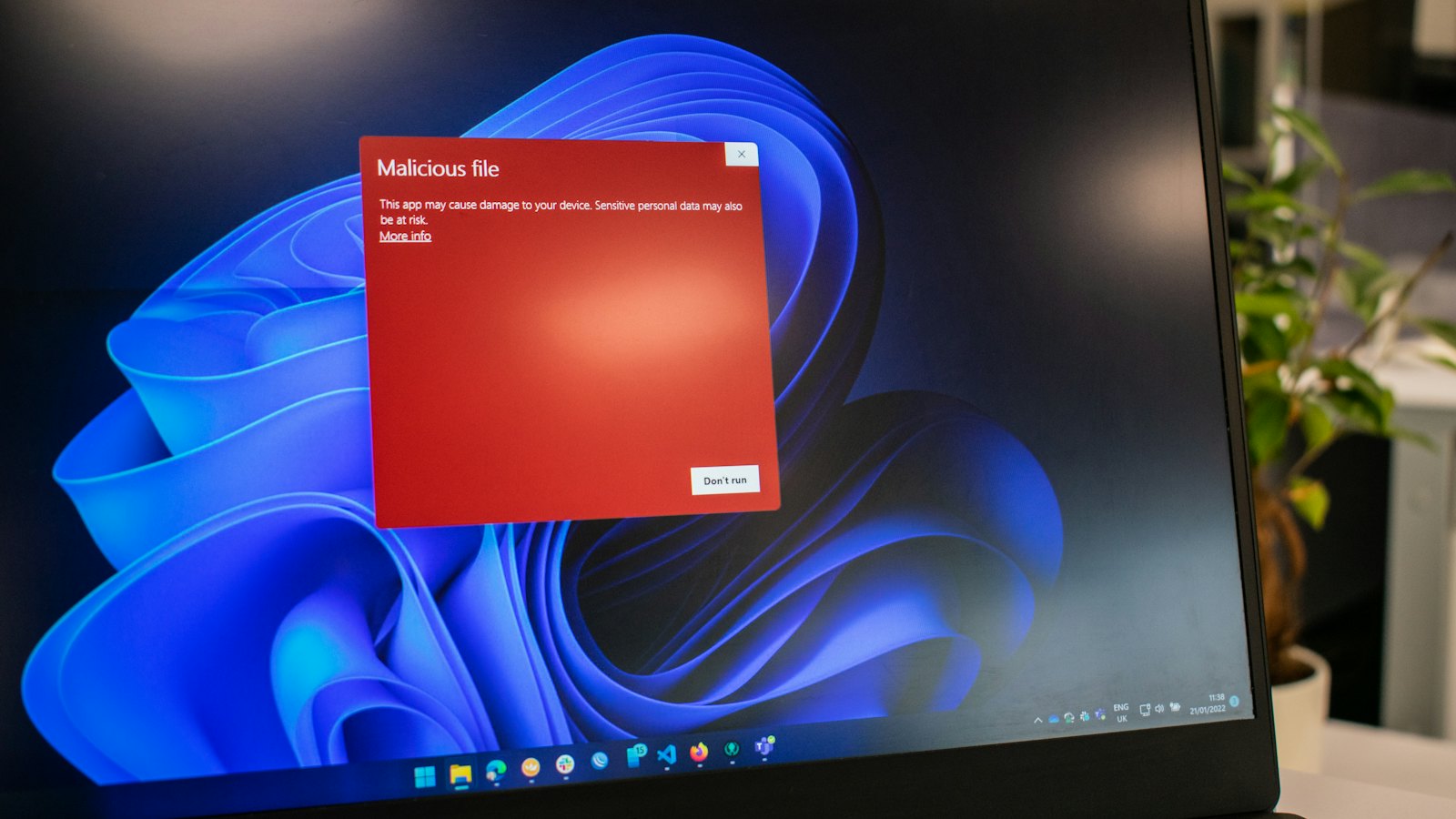A laptop screen showing a red malicious file warning