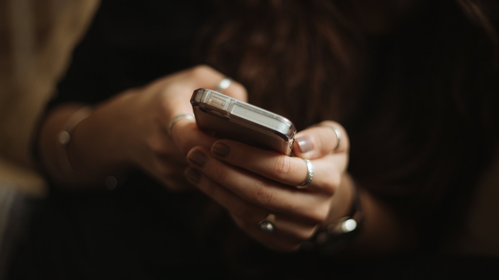 A person holding a smartphone in both hands in low light
