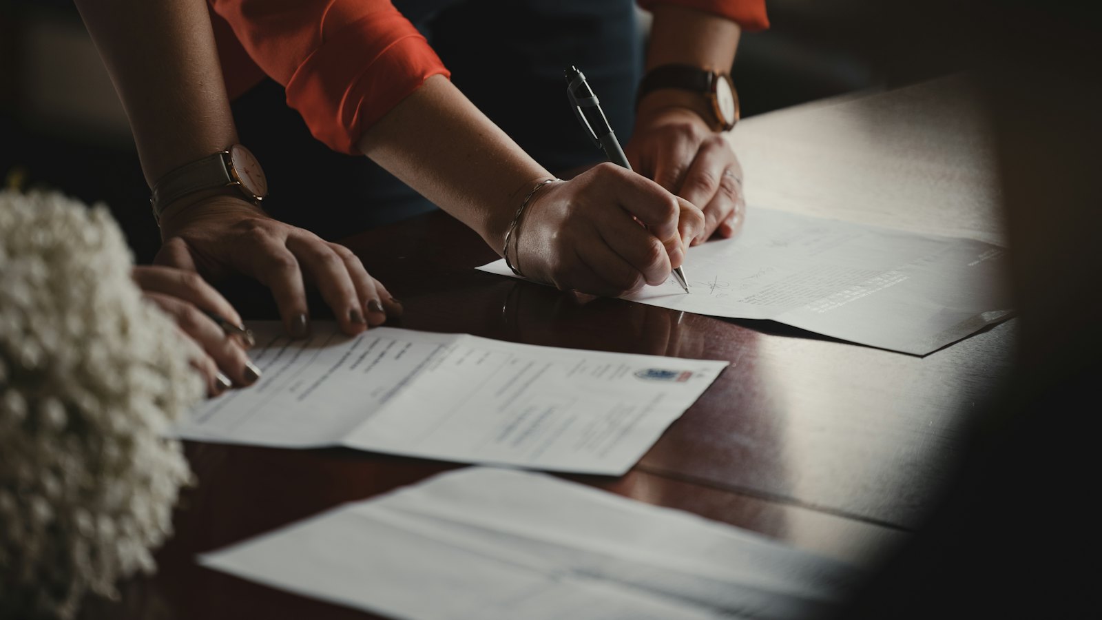 Two people writing on documents at a desk