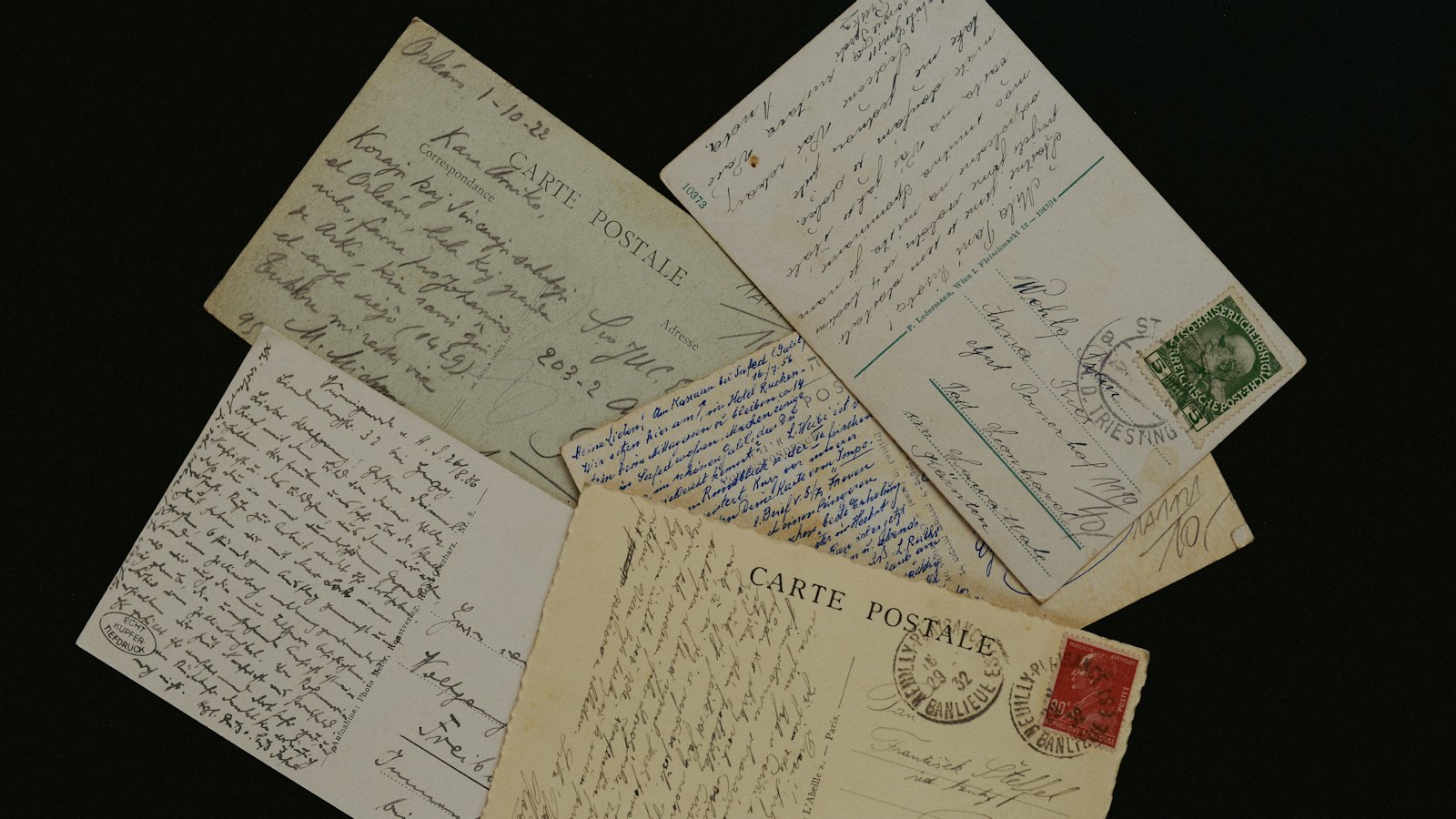 Old handwritten letters and postcards spread on a dark surface