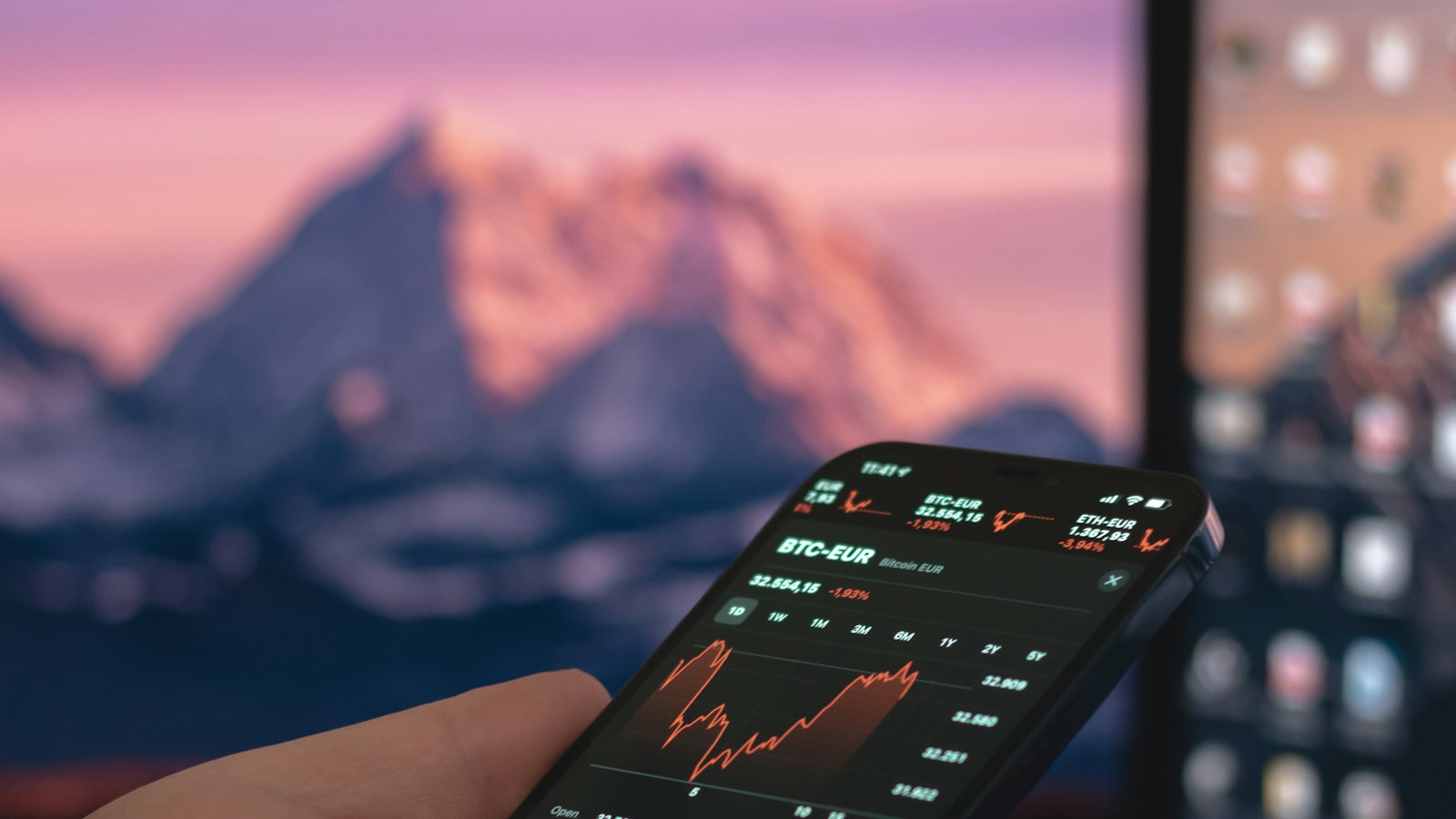 A person holding a phone with a trading app open