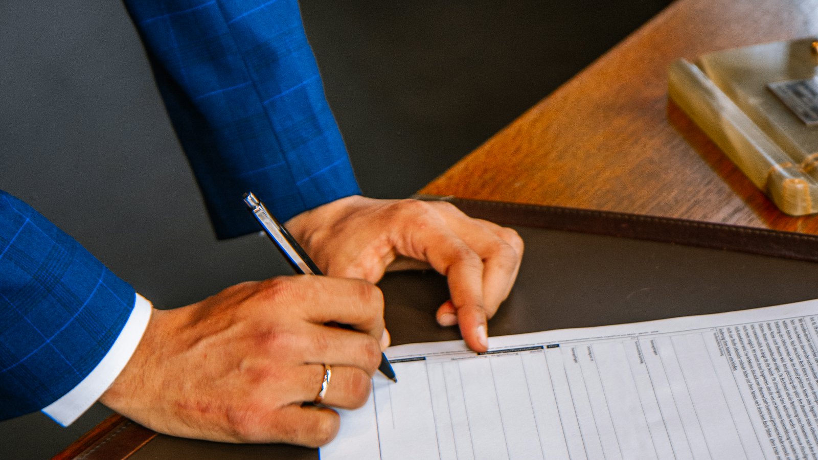 A man in a suit filling in a form with a pen