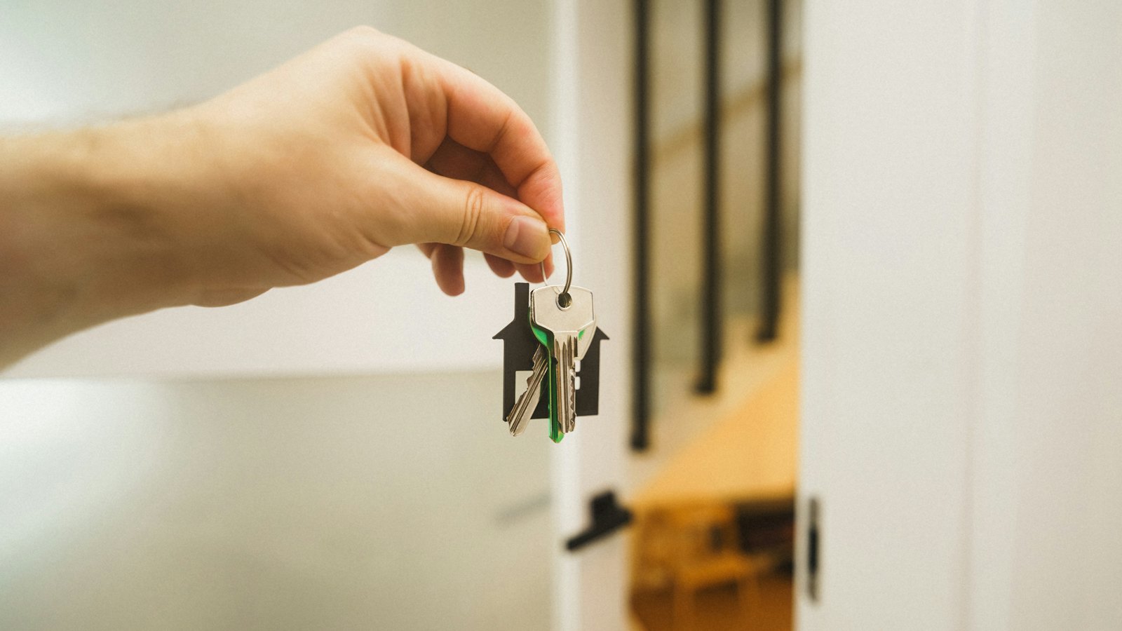 A hand holding house keys by a door
