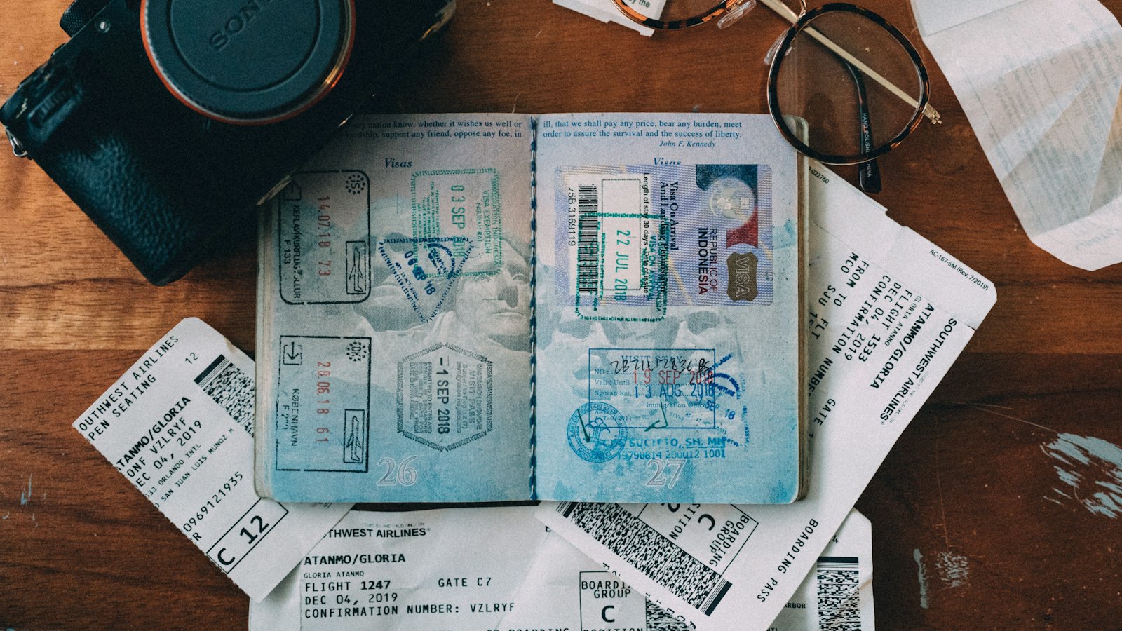 An open passport with visa stamps lying among travel papers
