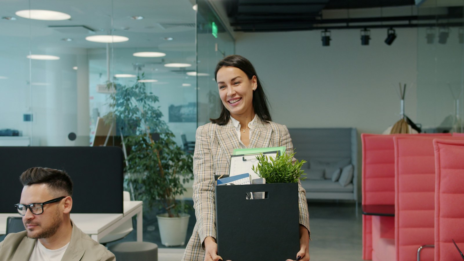 A woman carrying a box of belongings out of an office