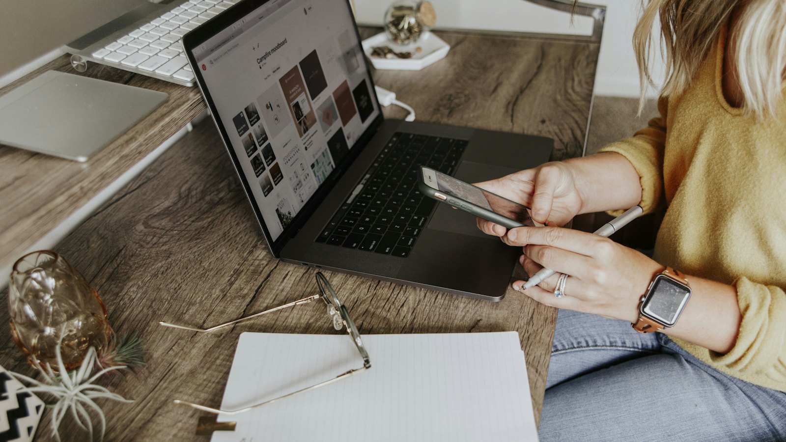 A woman using a phone next to a laptop