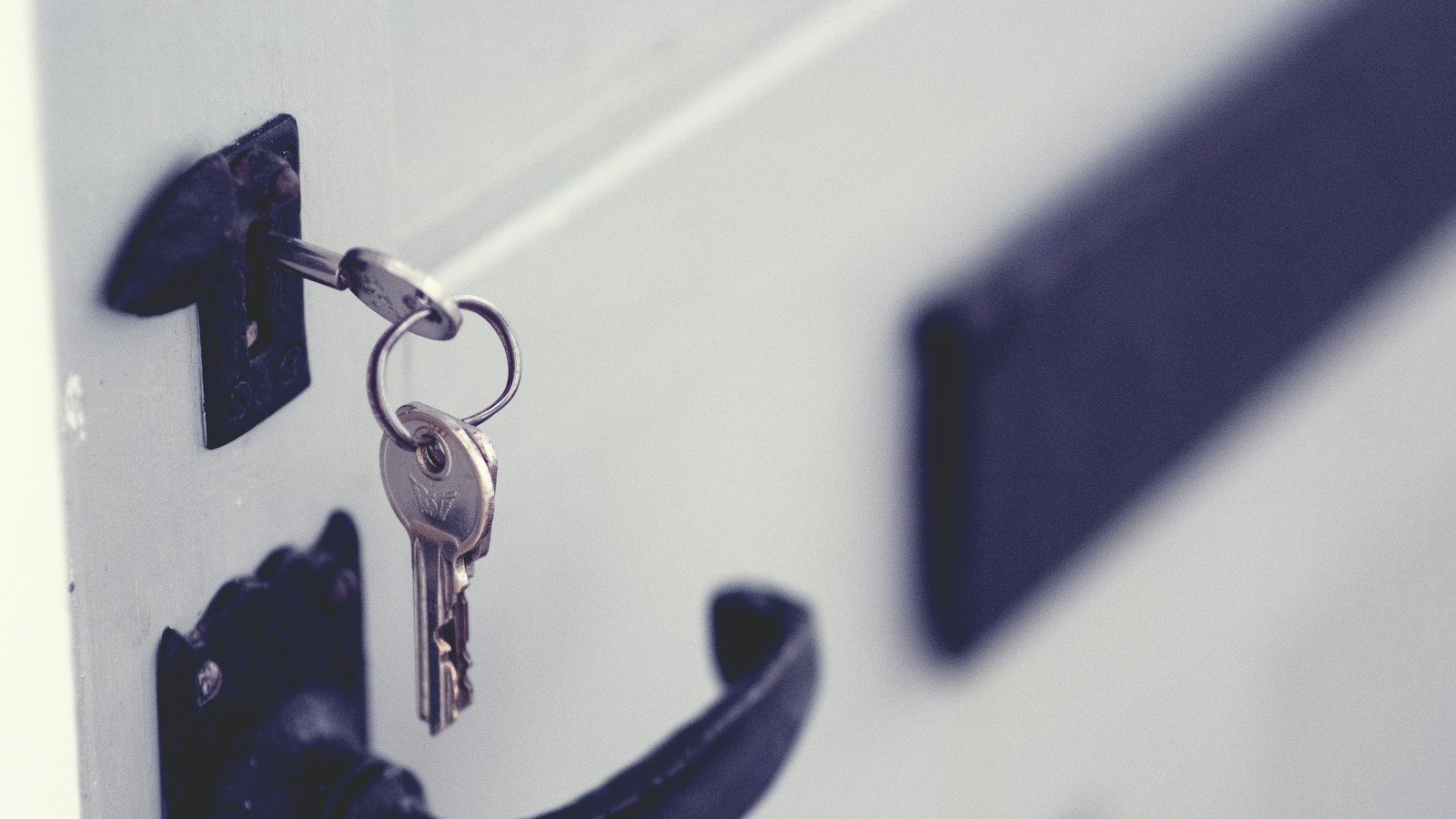 A set of keys hanging from a lock on a white door
