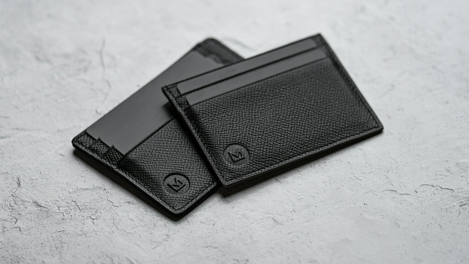 Two slim card wallets on a grey surface