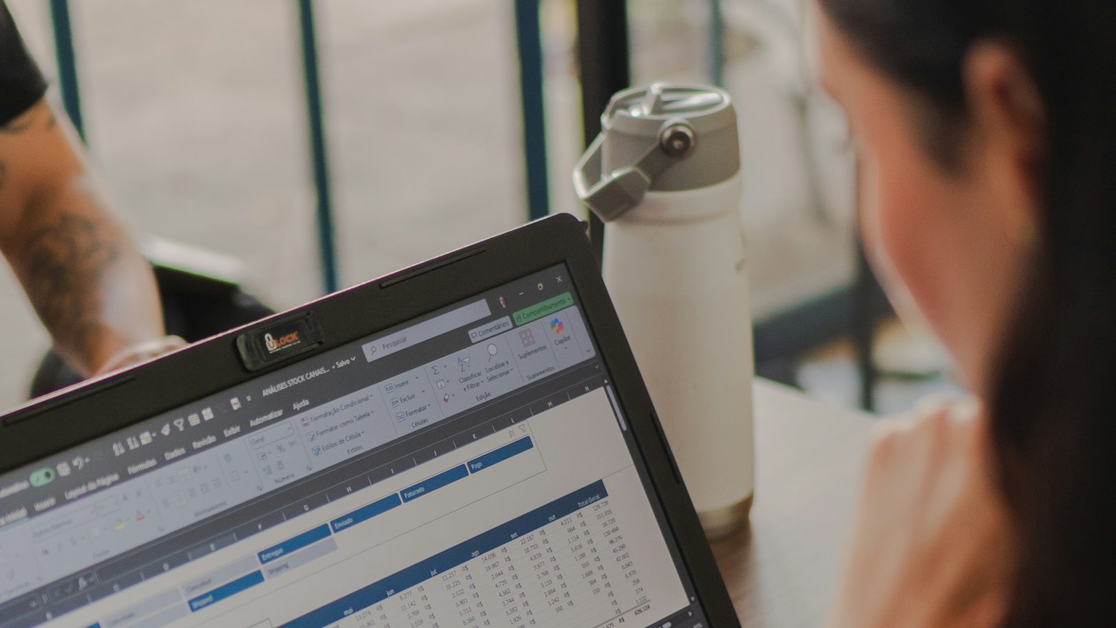 A woman working on a laptop showing a spreadsheet