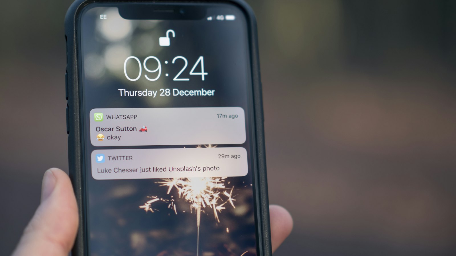 A hand holding a phone with notifications on its lock screen