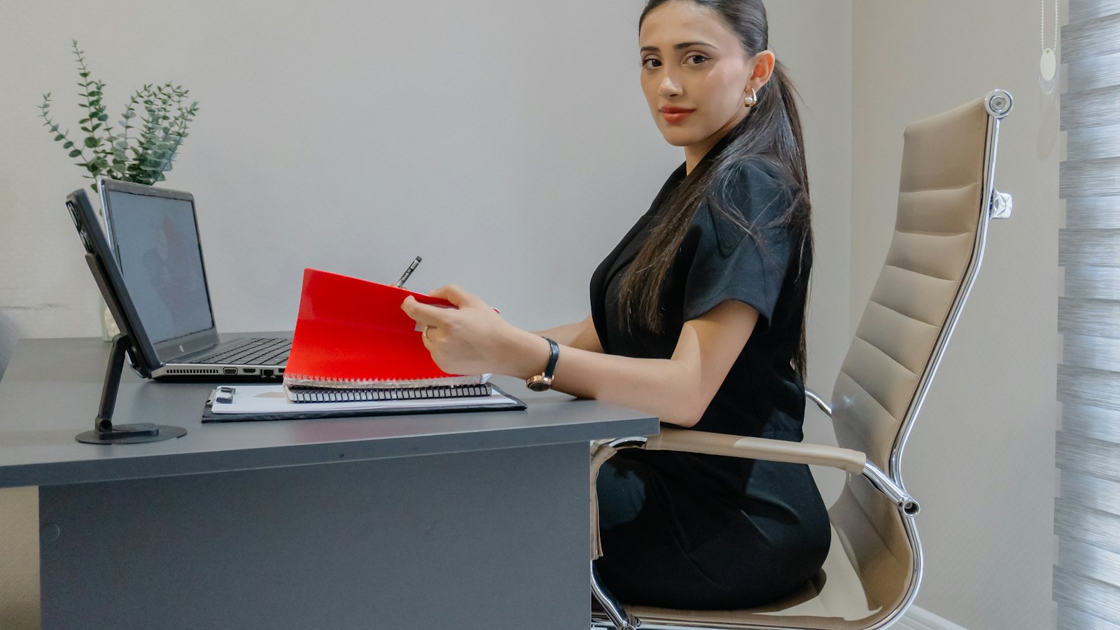 An office worker at a desk with a laptop and a folder