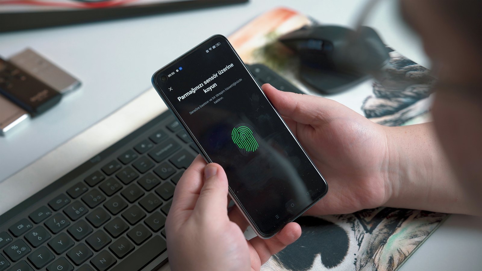 A person setting up fingerprint unlock on a phone at a desk