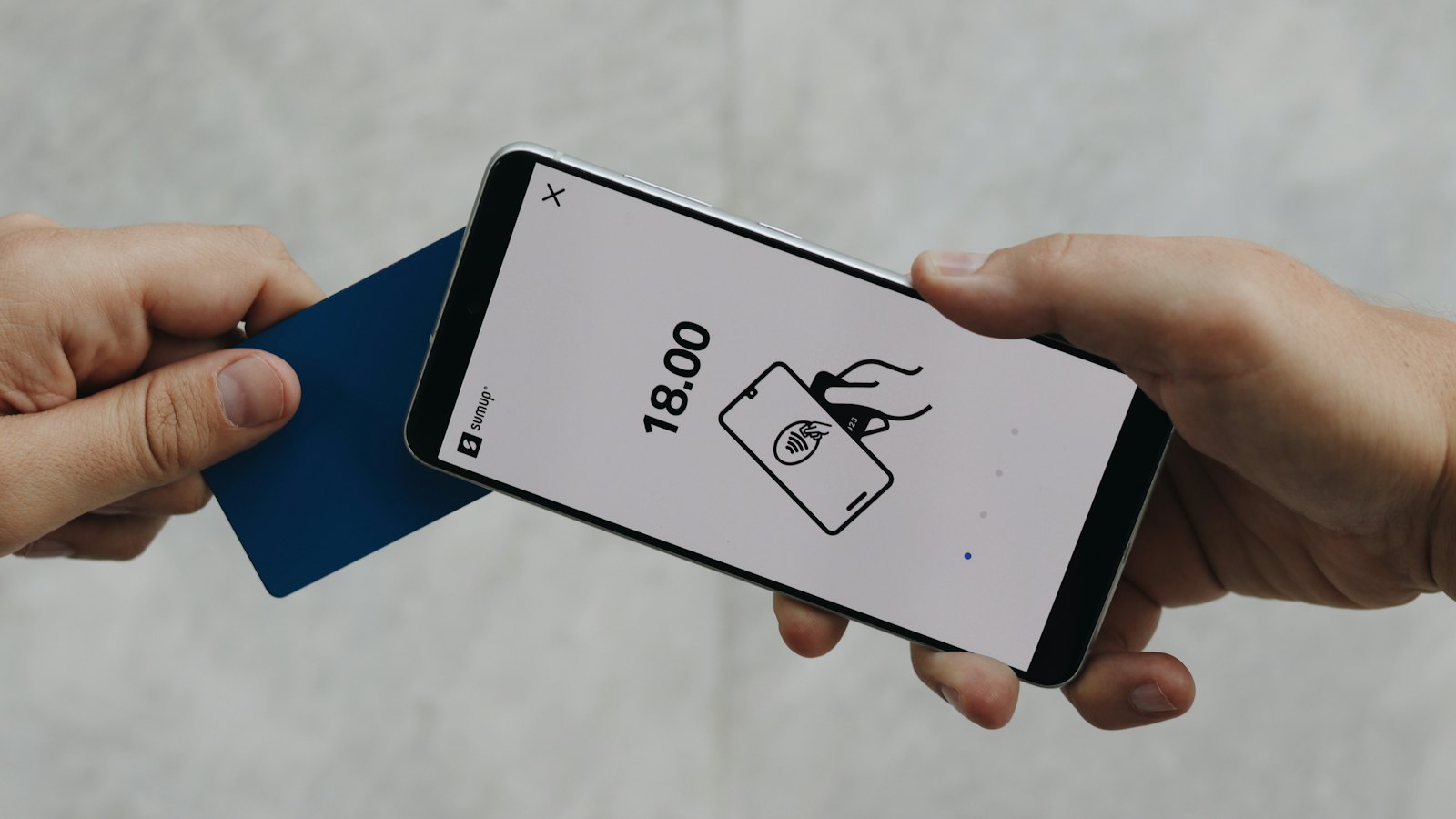 A phone showing a payment request next to a bank card