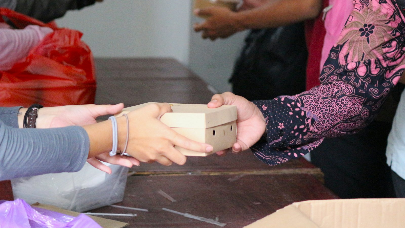 Two people passing a small package across a table