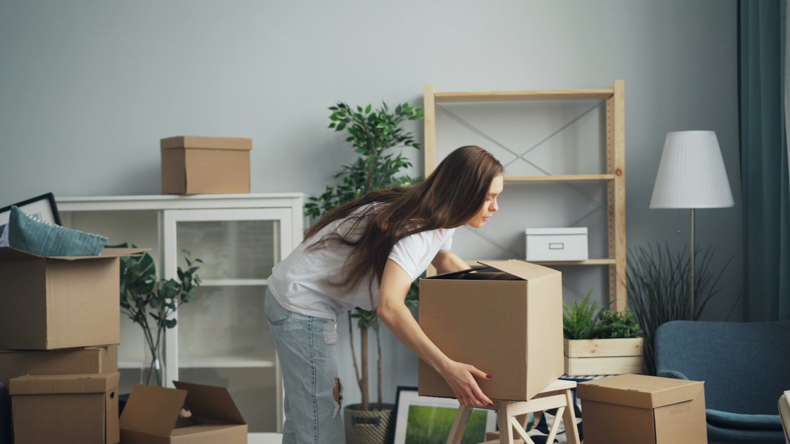 A woman packing cardboard boxes in a living room