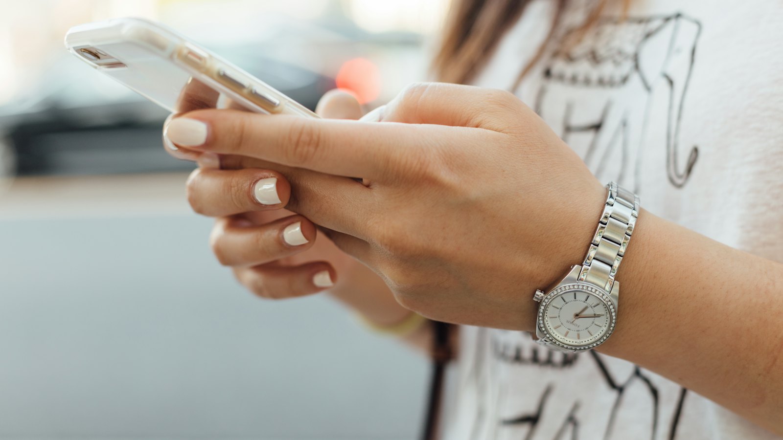 A woman in a wristwatch holding a phone outdoors