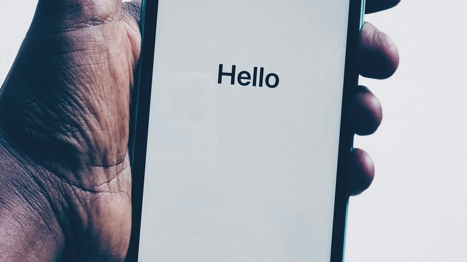 A hand holding a phone showing a greeting screen