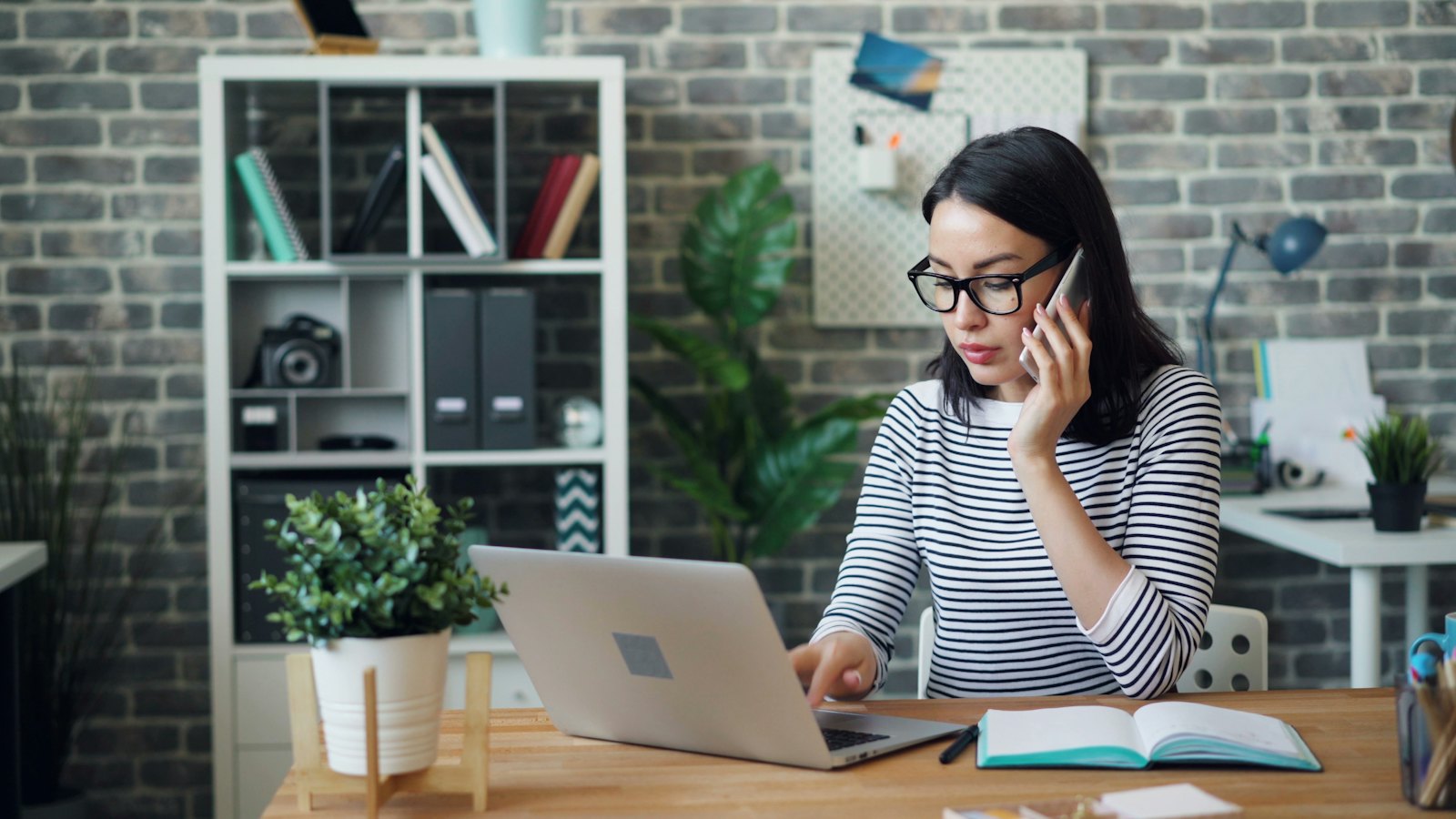 A woman on a phone call at her laptop in a home office