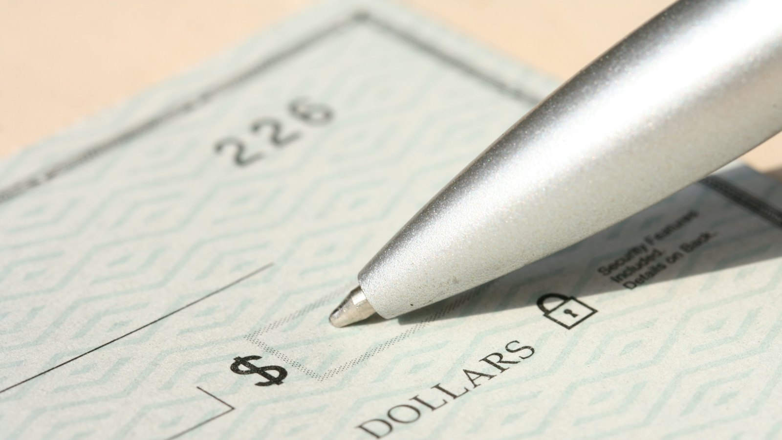 A pen resting on a cheque beside the dollars line