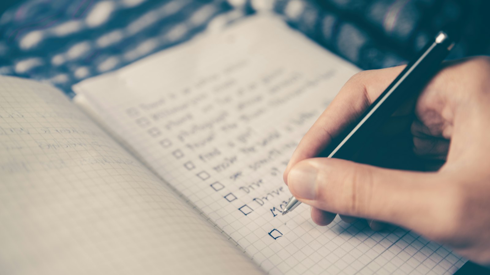 A hand ticking items on a handwritten checklist
