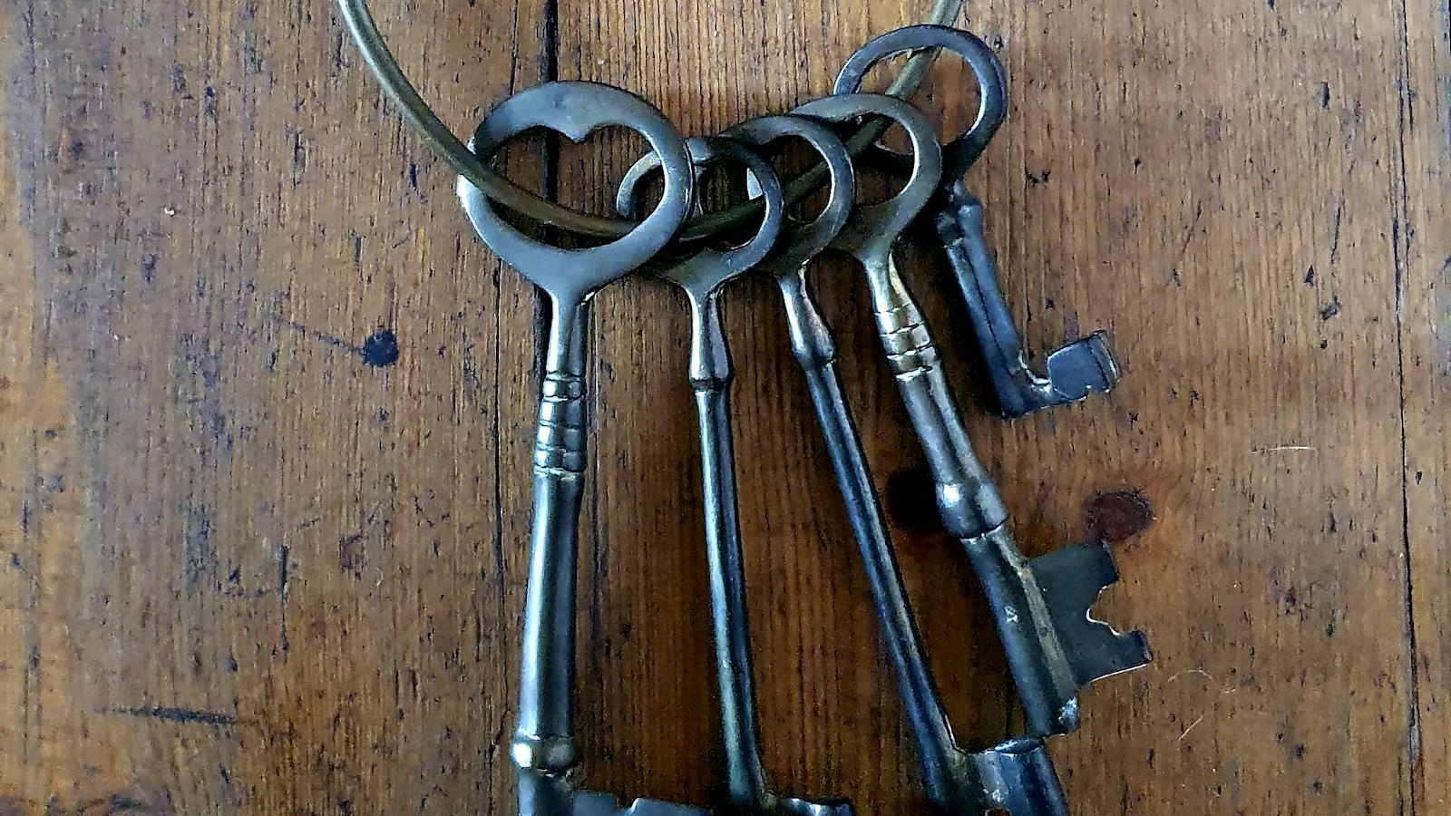 A ring of old iron skeleton keys on a wooden table