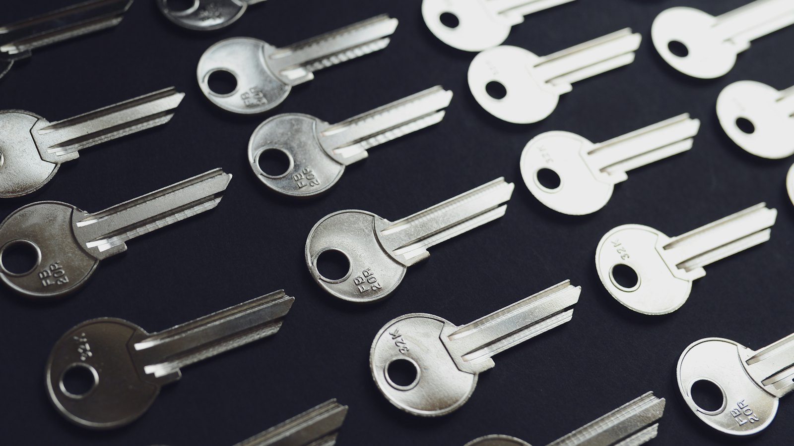 Rows of identical silver keys laid out on a dark surface