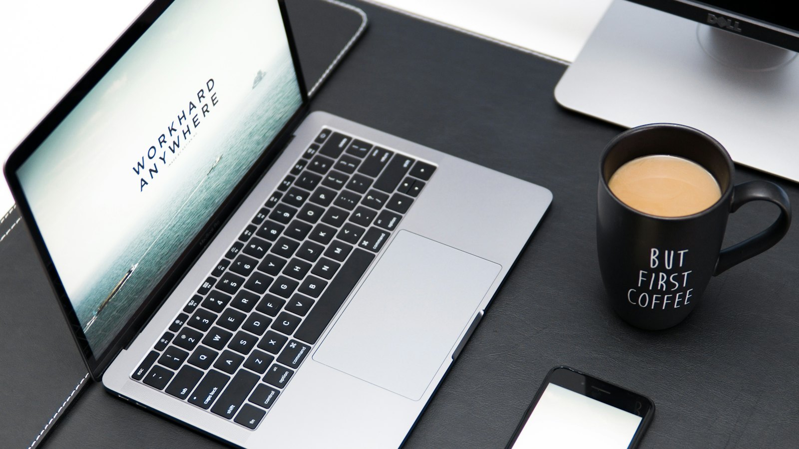 A laptop, a phone and a coffee mug on a desk