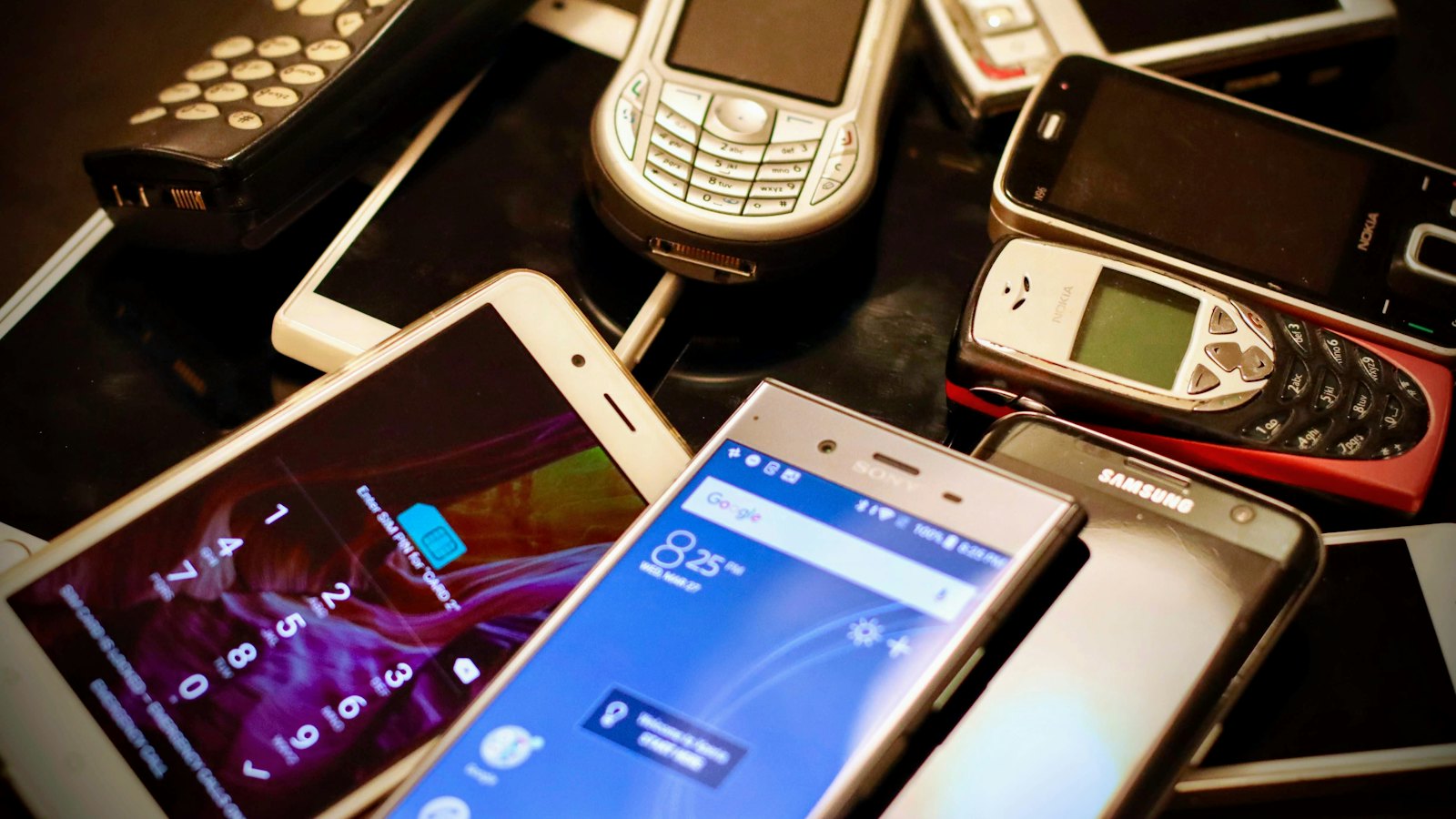 A pile of old mobile phones of different ages
