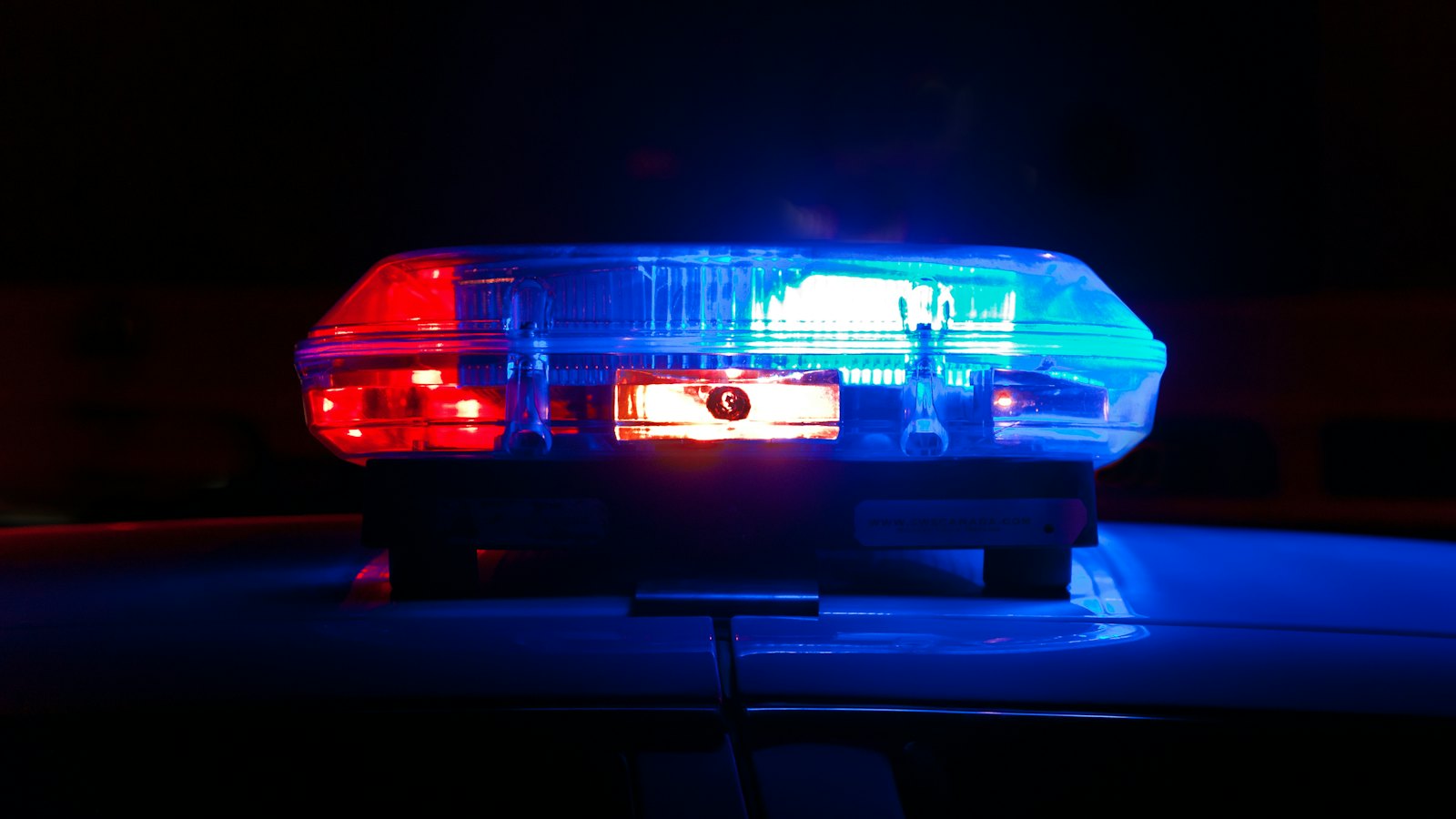 A police light bar glowing red and blue in the dark