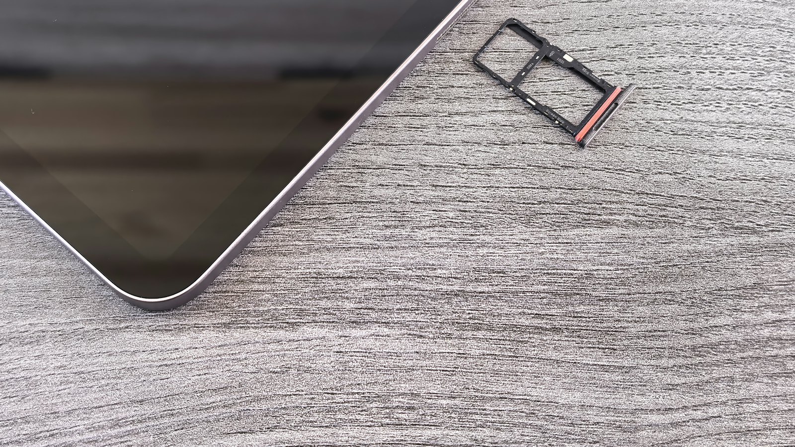 A SIM card tray lying beside a smartphone