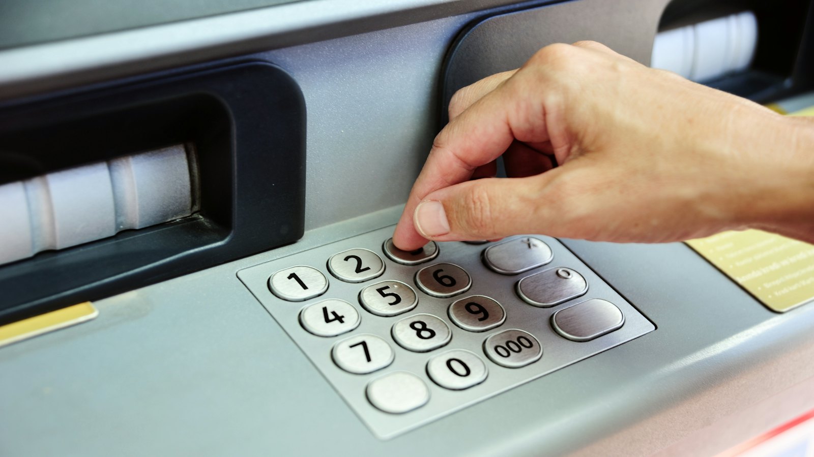 A hand entering a PIN on an ATM keypad