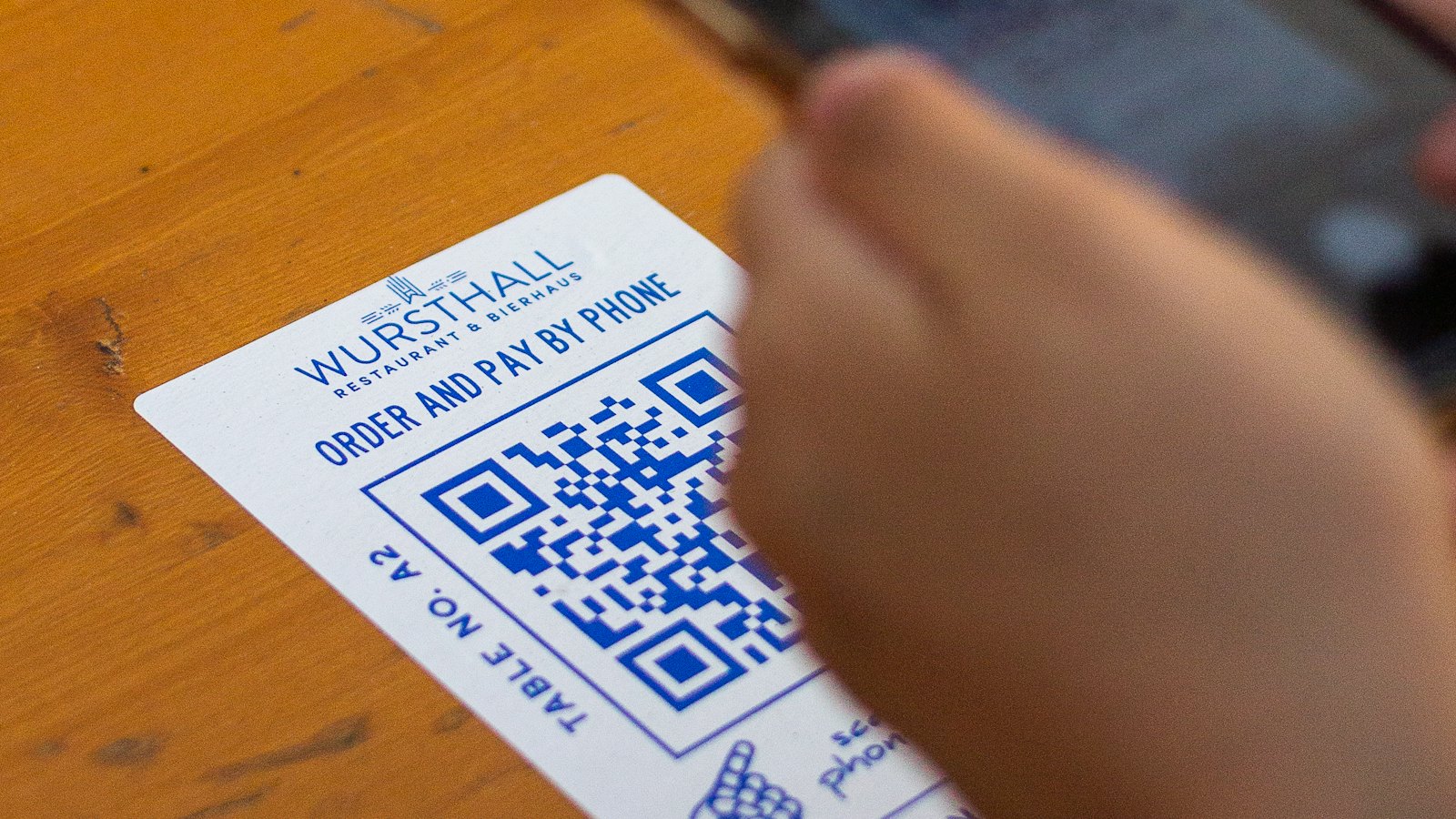 A phone being held over a QR code printed on a table card in a restaurant