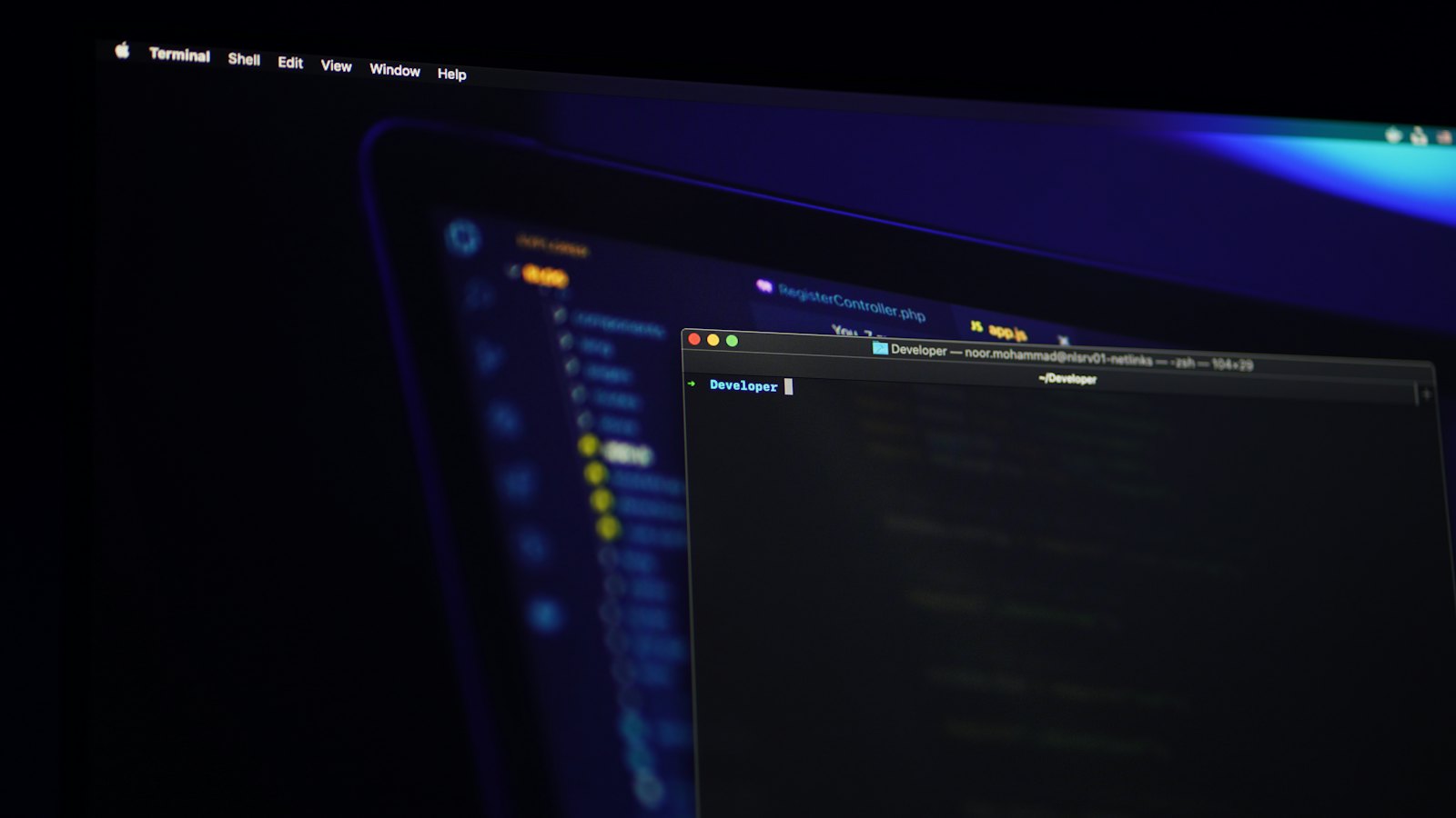 A laptop screen showing a terminal window in a dark room