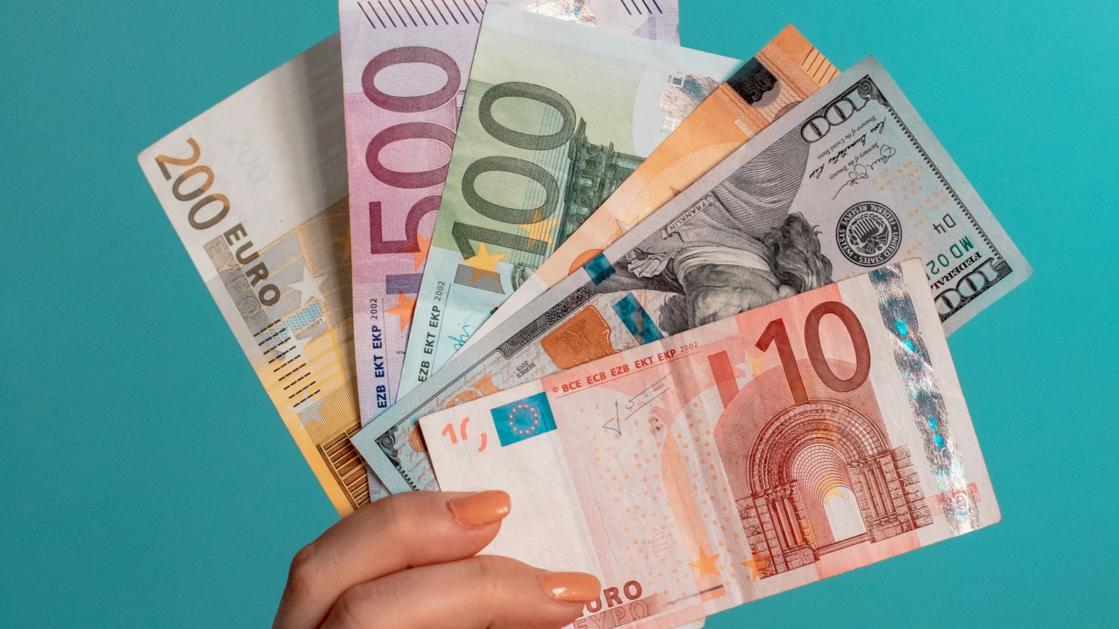 A hand holding assorted banknotes
