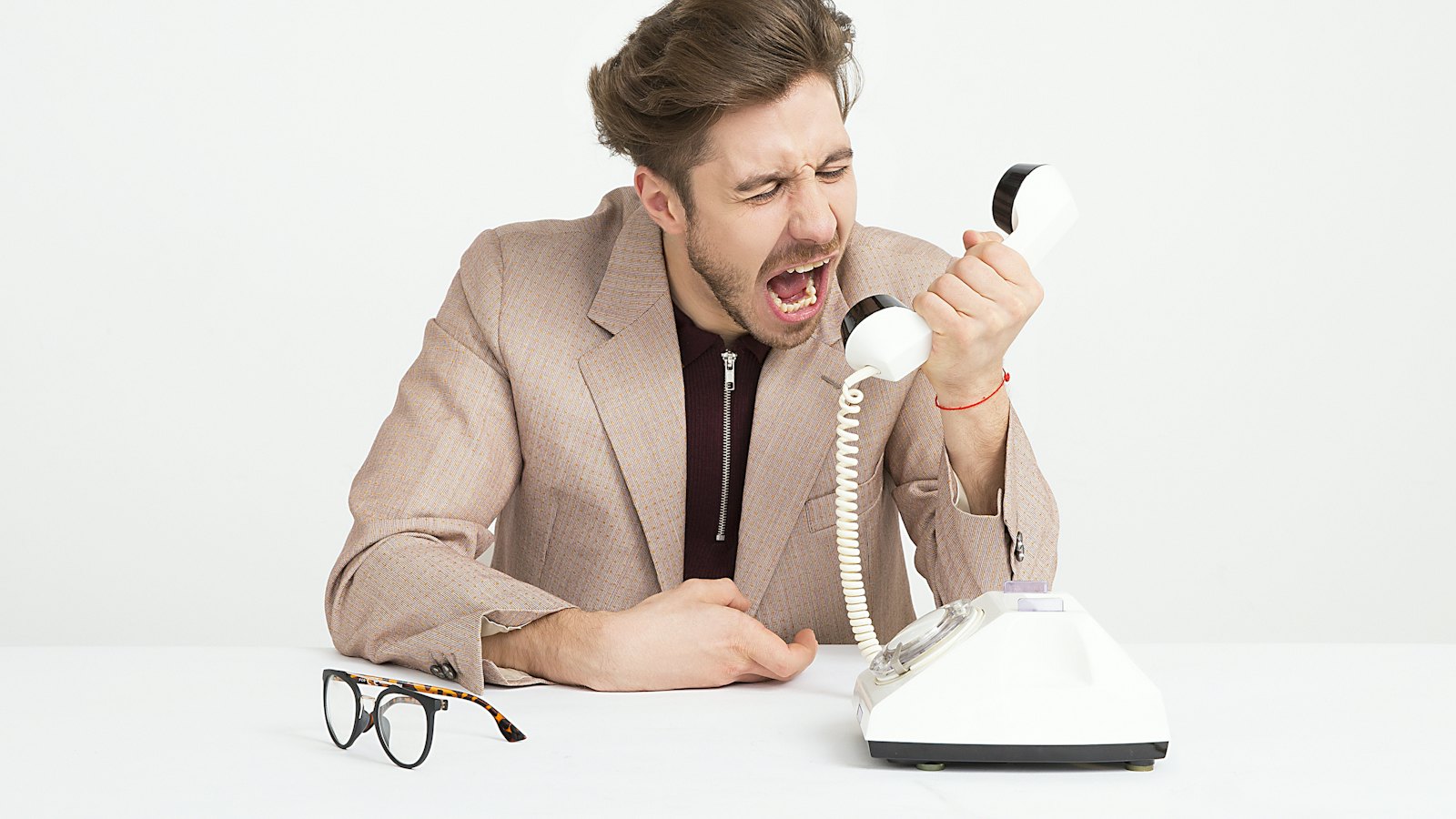A frustrated man shouting into an old telephone receiver