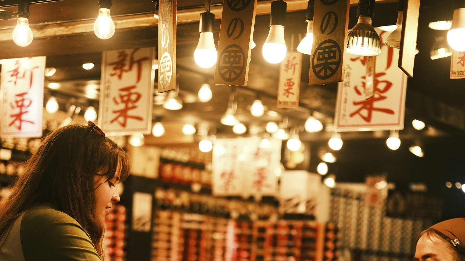 A busy market stall lit by hanging bulbs