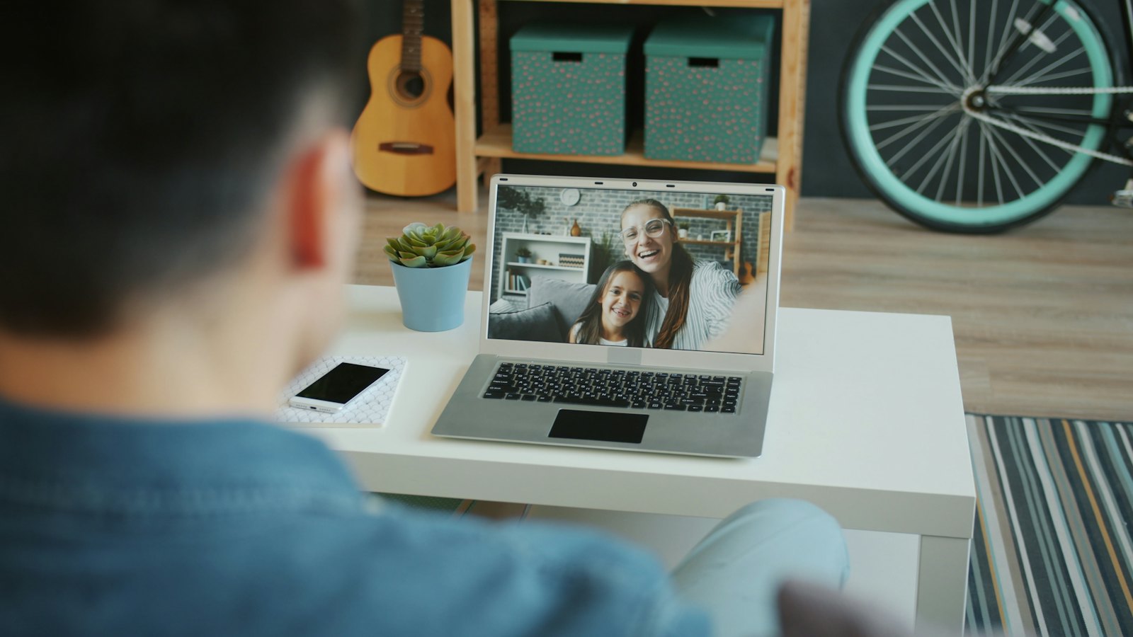 A man on a video call with two smiling women on his laptop