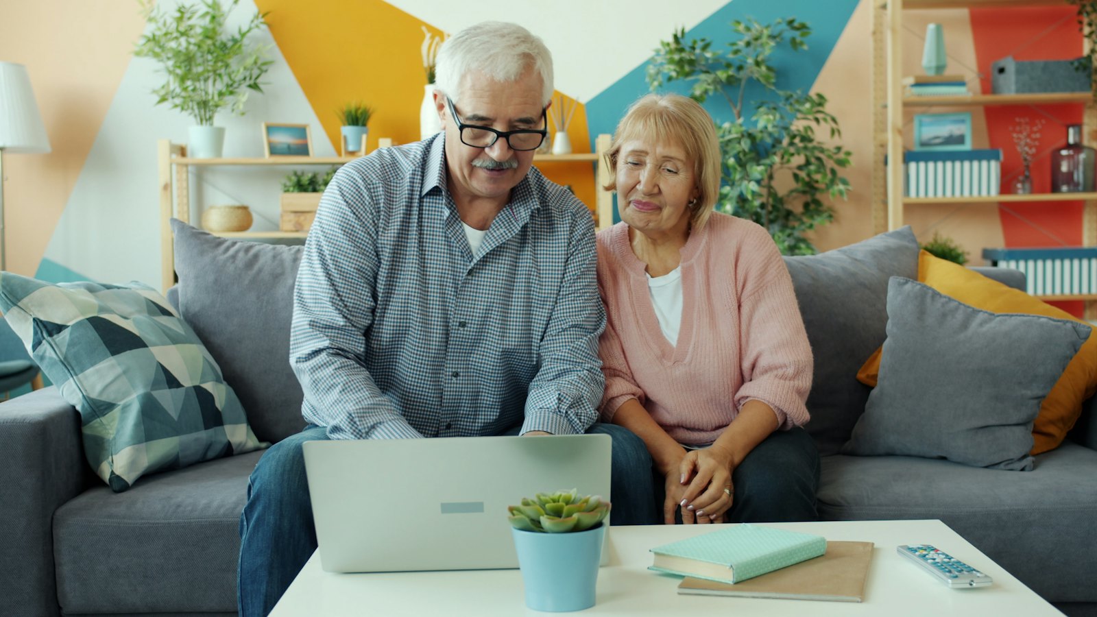 An older couple on a sofa looking at a laptop together