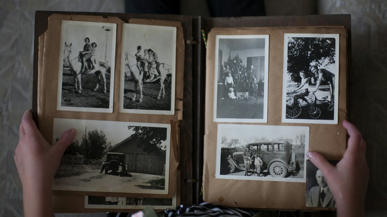 Hands holding open an old album of black and white family photos