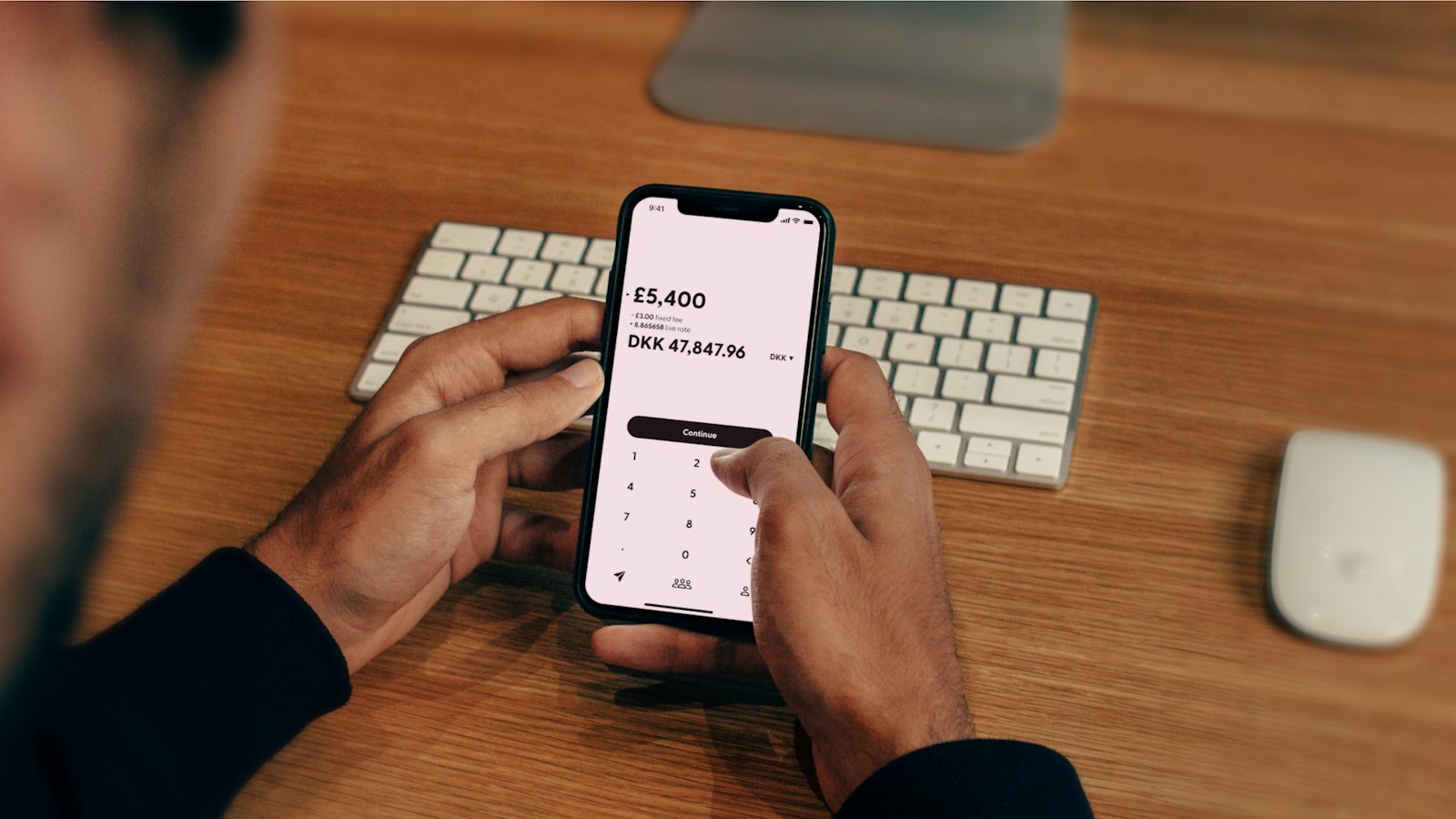 A man using a phone to send money at his desk