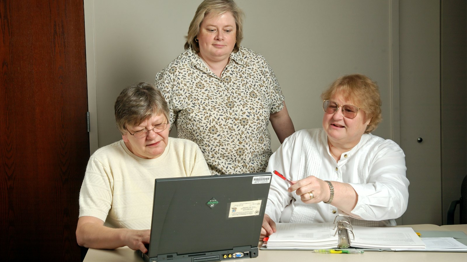 Three older women looking at a laptop together