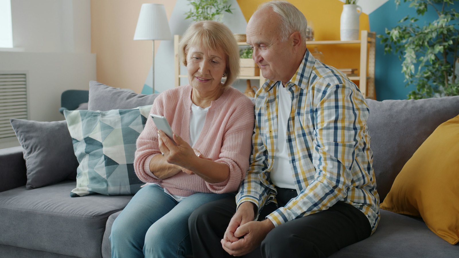 An older couple on a sofa looking at a smartphone together