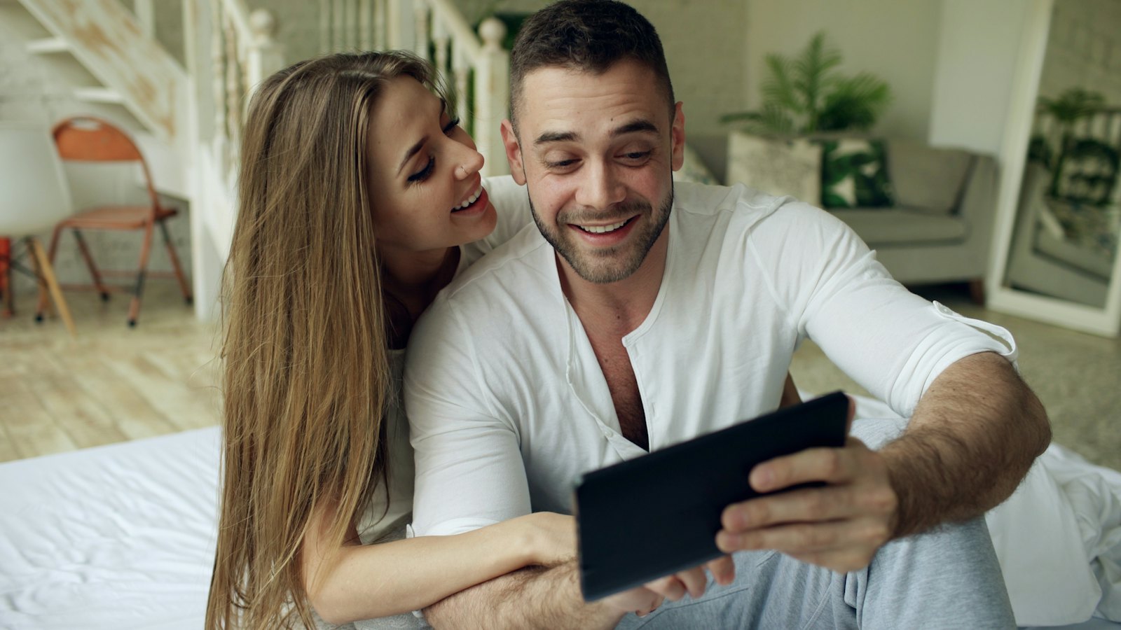 A smiling couple looking at a tablet together
