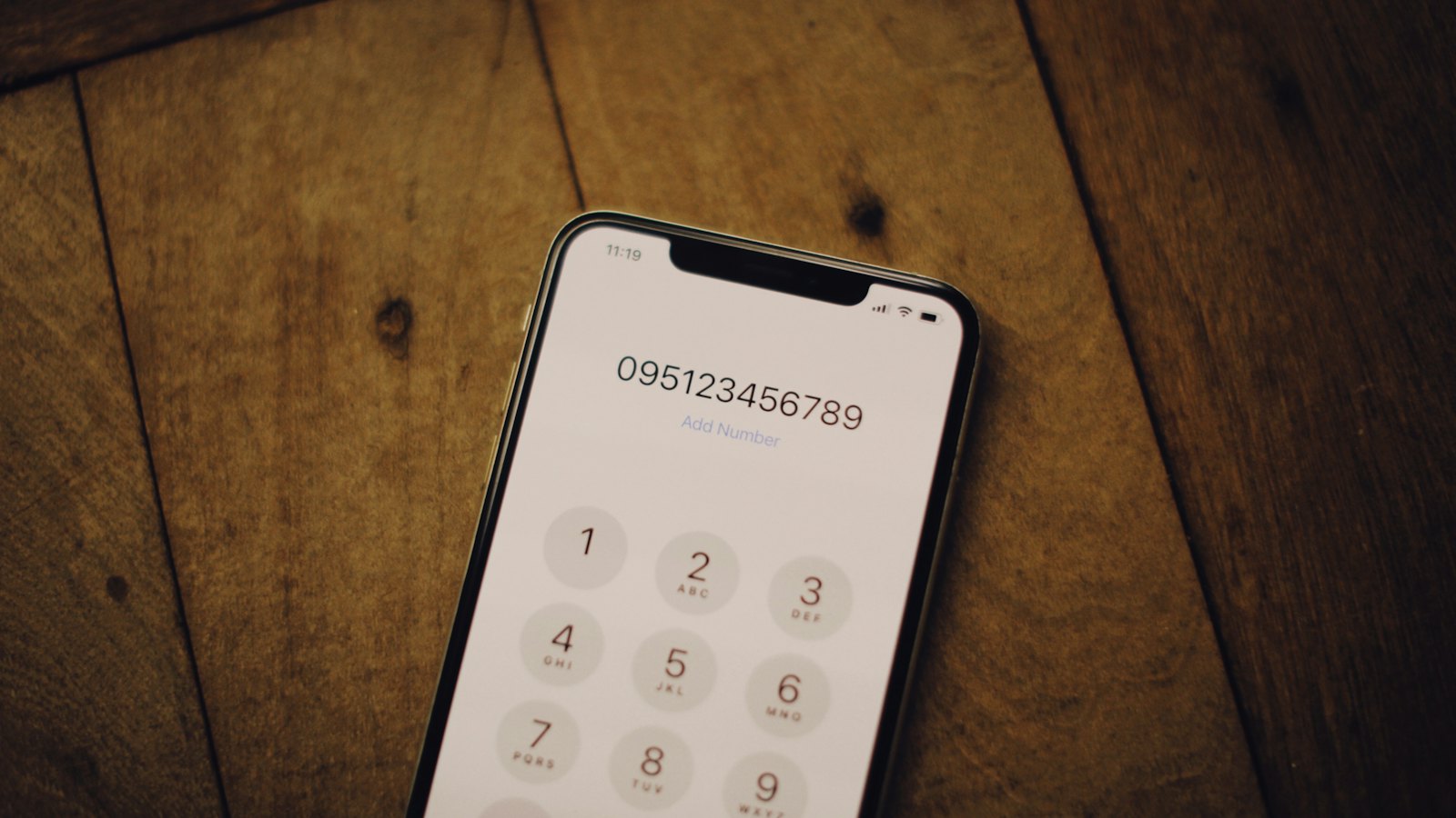 A smartphone showing a dial pad on a wooden table