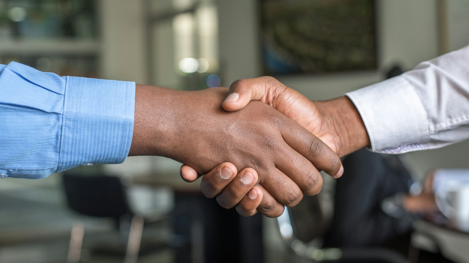 Two people shaking hands across an office