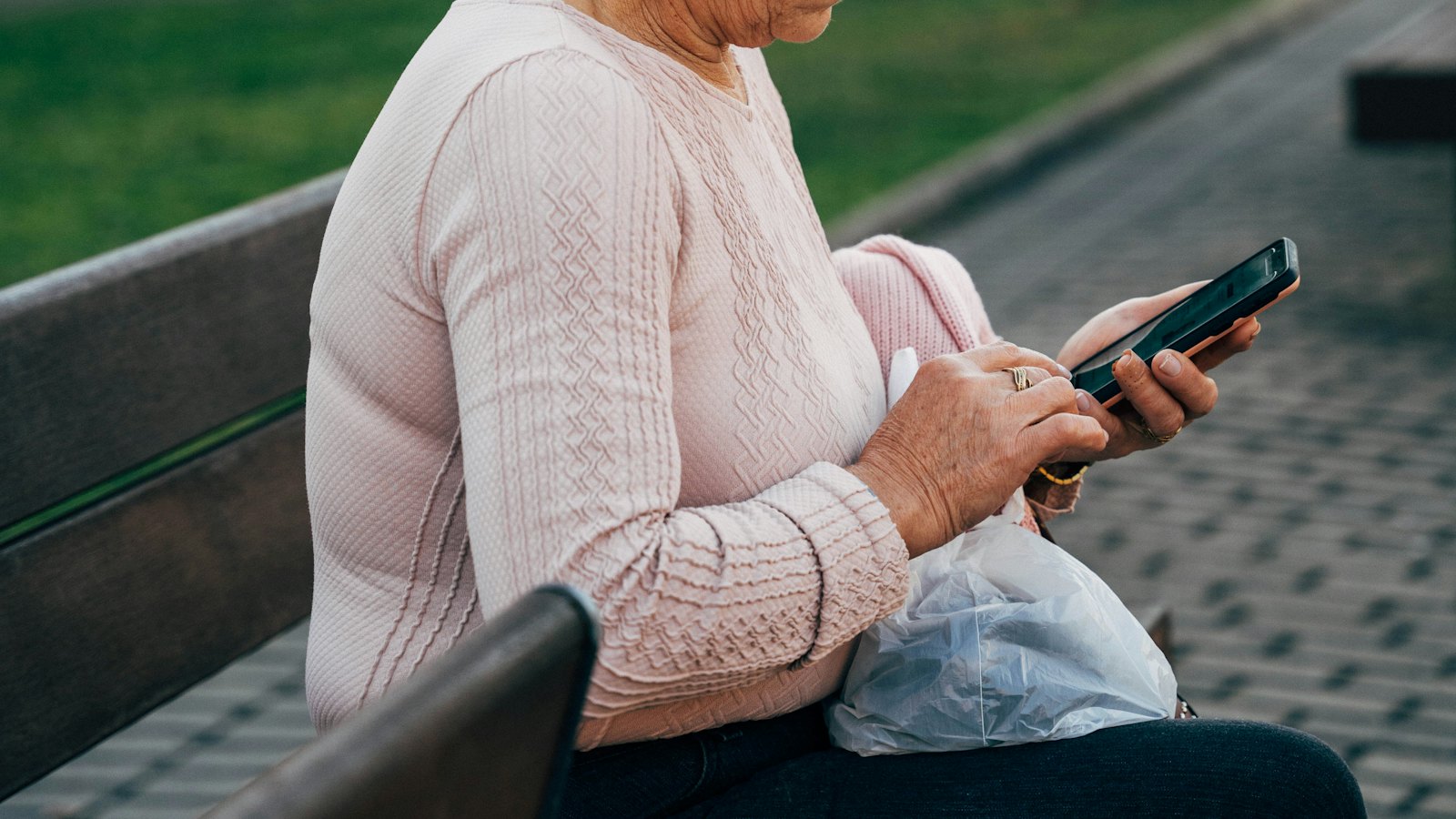 A woman sitting on a bench checking her phone