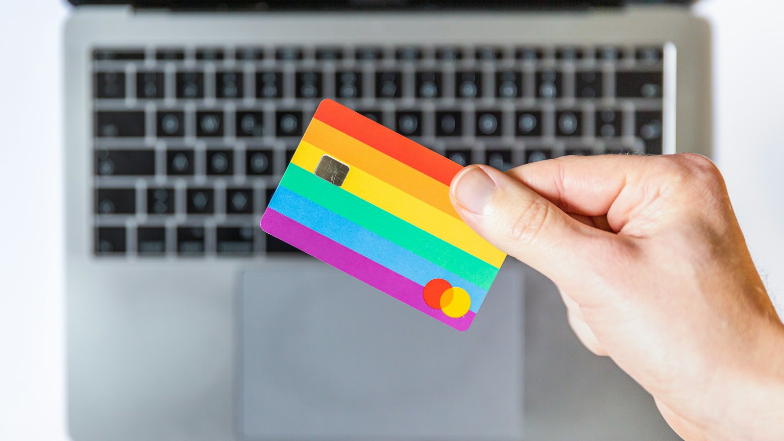 A hand holding a card in front of a laptop