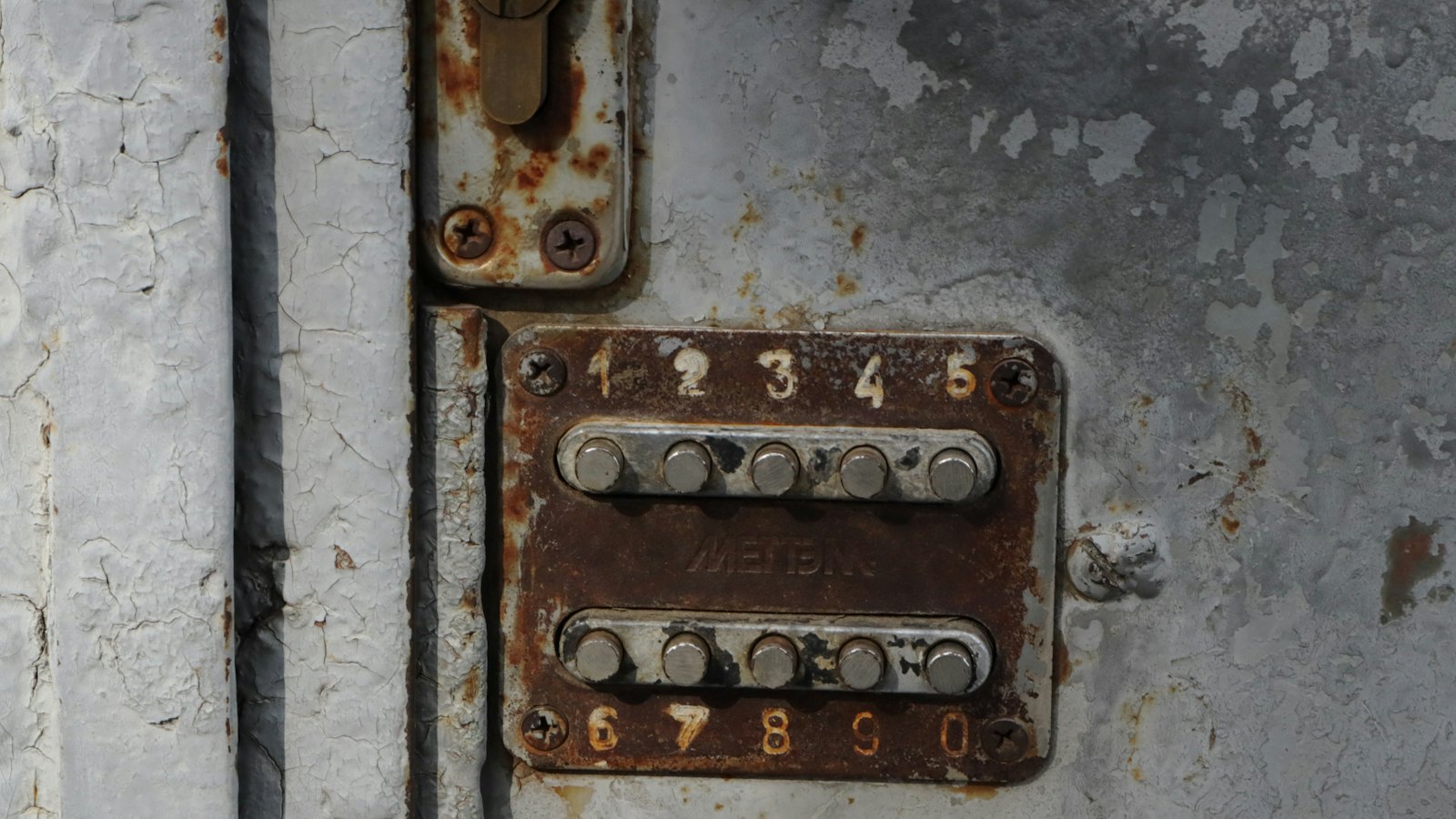 A worn metal keypad on a door