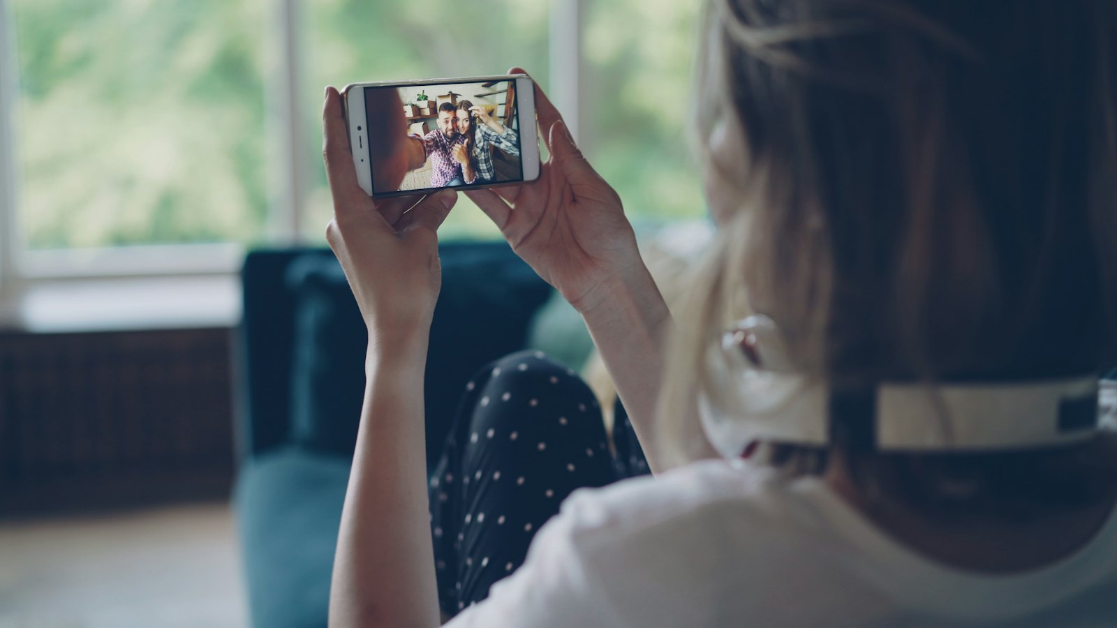 A woman holding up her phone to watch a video