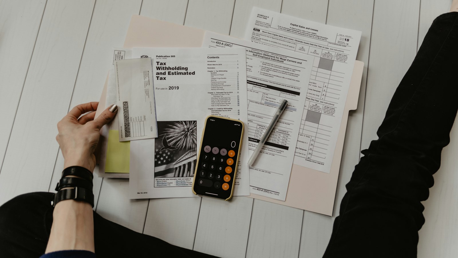 Tax forms, a calculator and a phone spread on a desk
